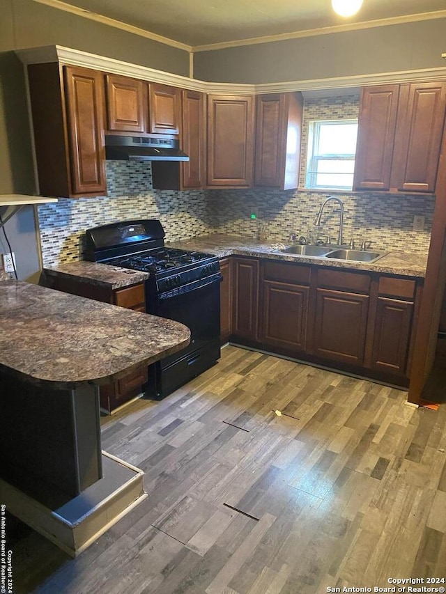 kitchen with black range with gas stovetop, sink, crown molding, decorative backsplash, and light hardwood / wood-style floors