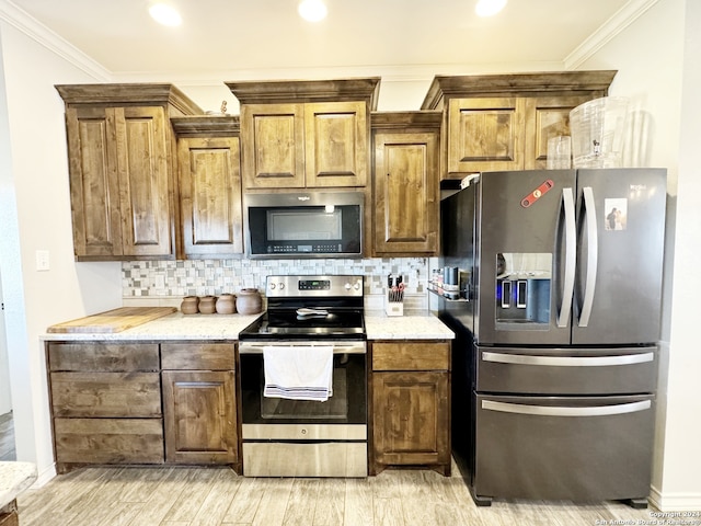 kitchen with appliances with stainless steel finishes, light hardwood / wood-style floors, tasteful backsplash, and crown molding