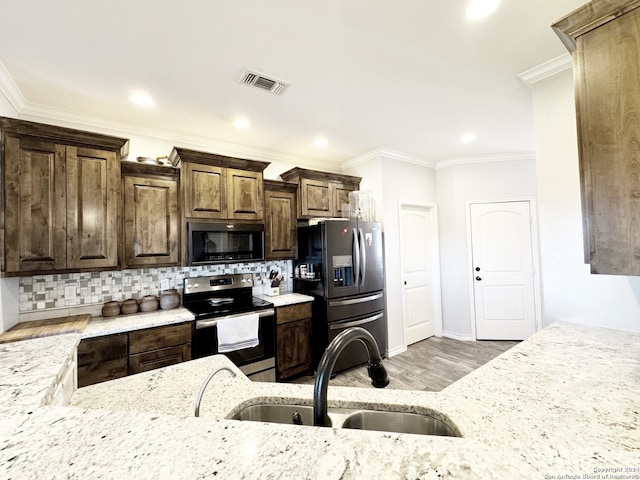 kitchen featuring decorative backsplash, appliances with stainless steel finishes, ornamental molding, sink, and light hardwood / wood-style floors