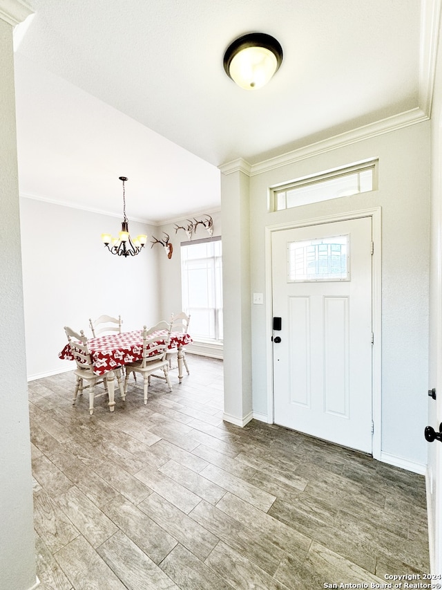 foyer entrance with crown molding, hardwood / wood-style floors, and a chandelier