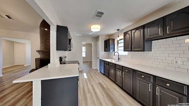 kitchen with sink, light hardwood / wood-style floors, decorative light fixtures, decorative backsplash, and appliances with stainless steel finishes