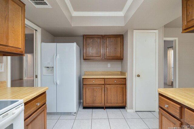 kitchen featuring white refrigerator with ice dispenser, light tile patterned floors, stove, and a raised ceiling