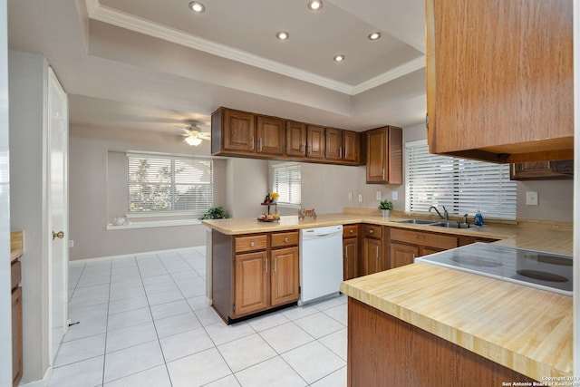 kitchen featuring sink, kitchen peninsula, crown molding, white dishwasher, and a tray ceiling