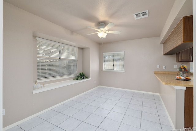 unfurnished dining area with ceiling fan and light tile patterned floors