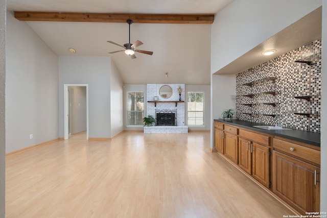 living room with ceiling fan, sink, a brick fireplace, high vaulted ceiling, and light hardwood / wood-style floors