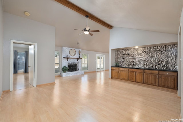 unfurnished living room featuring beamed ceiling, light wood-type flooring, a fireplace, and high vaulted ceiling