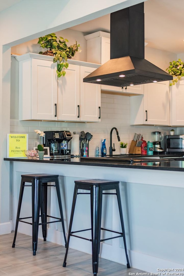 802 Piedmont Ave, San Antonio, TX 78210 - kitchen with island range hood, stainless steel microwave, dark countertops, and white cabinetry