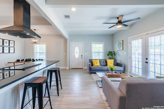 living room with french doors, ceiling fan with notable chandelier, and light wood-type flooring