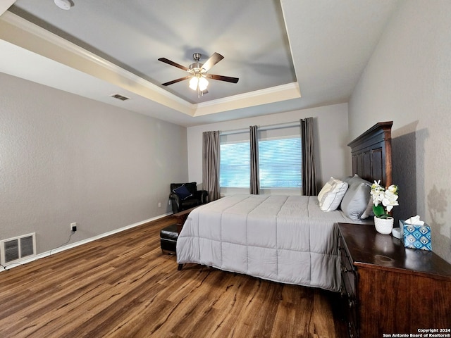 bedroom featuring hardwood / wood-style flooring, a raised ceiling, and ceiling fan