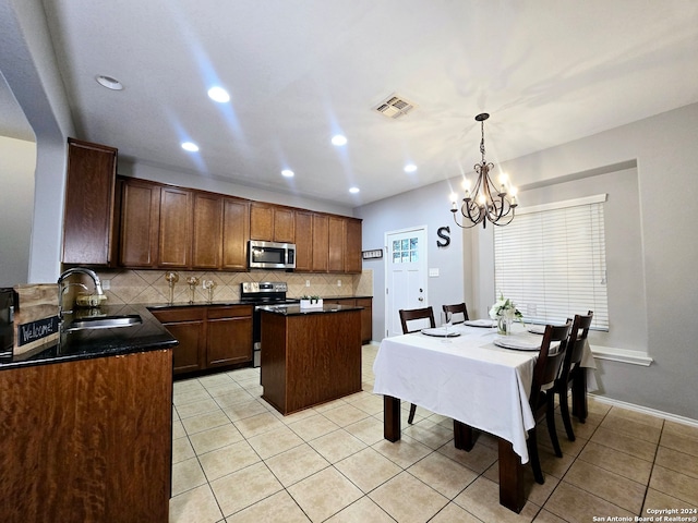 kitchen with appliances with stainless steel finishes, sink, decorative light fixtures, a chandelier, and a kitchen island