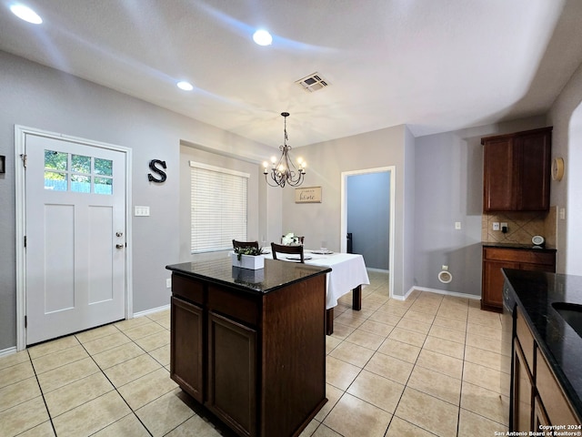 kitchen with decorative light fixtures, light tile patterned floors, a notable chandelier, a kitchen island, and dark brown cabinets