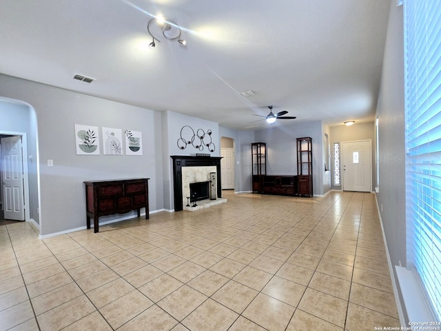 unfurnished living room featuring a premium fireplace, light tile patterned flooring, and ceiling fan