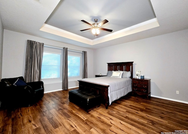 bedroom featuring a raised ceiling, ceiling fan, dark wood-type flooring, and crown molding