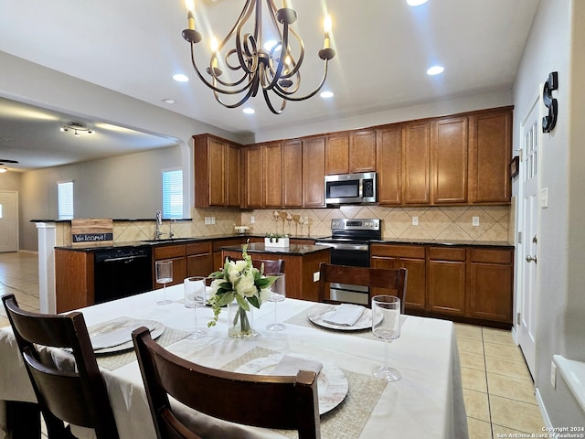 kitchen with sink, a kitchen island, pendant lighting, light tile patterned flooring, and appliances with stainless steel finishes