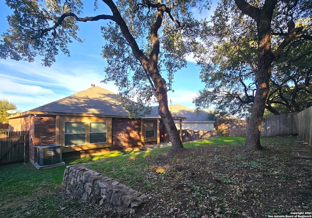 back of house with a yard and central AC