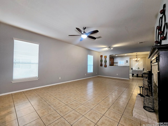 unfurnished living room featuring ceiling fan with notable chandelier and light tile patterned flooring