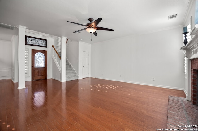 unfurnished living room with crown molding, dark hardwood / wood-style flooring, ceiling fan, and a brick fireplace