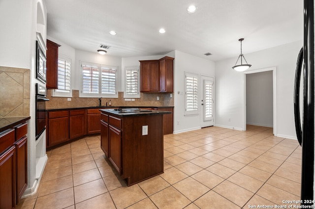 kitchen with black fridge, a kitchen island, a healthy amount of sunlight, and light tile patterned flooring