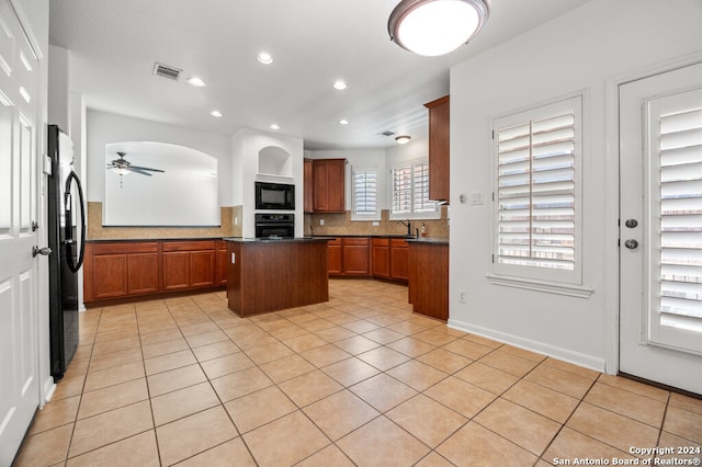 kitchen with ceiling fan, a center island, backsplash, light tile patterned floors, and black appliances