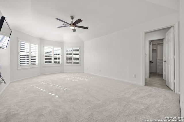 carpeted spare room featuring ceiling fan and vaulted ceiling