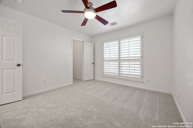 empty room with ceiling fan and light carpet