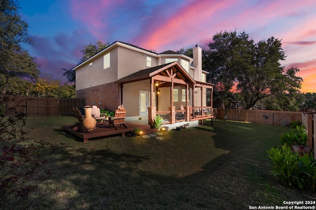 back house at dusk with a deck and a yard