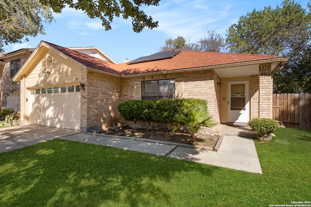 single story home featuring a front yard, solar panels, and a garage