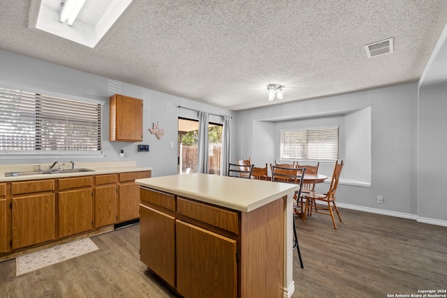 kitchen featuring a center island, light hardwood / wood-style floors, sink, and a textured ceiling