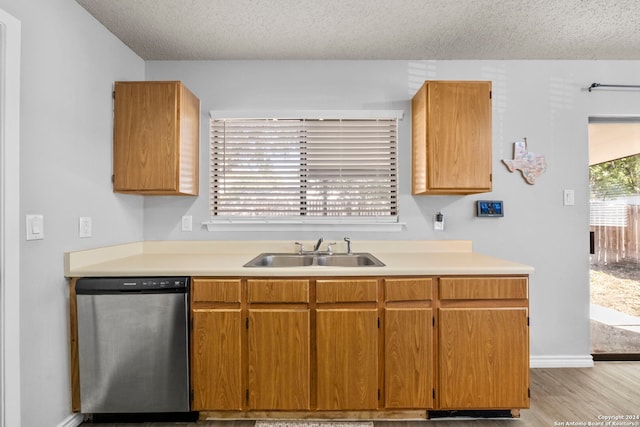 kitchen featuring a textured ceiling, light hardwood / wood-style flooring, stainless steel dishwasher, and sink