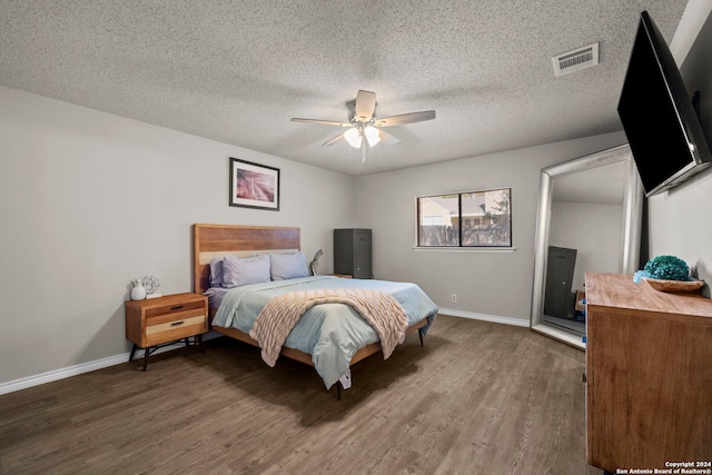 bedroom featuring a textured ceiling, ceiling fan, and dark wood-type flooring