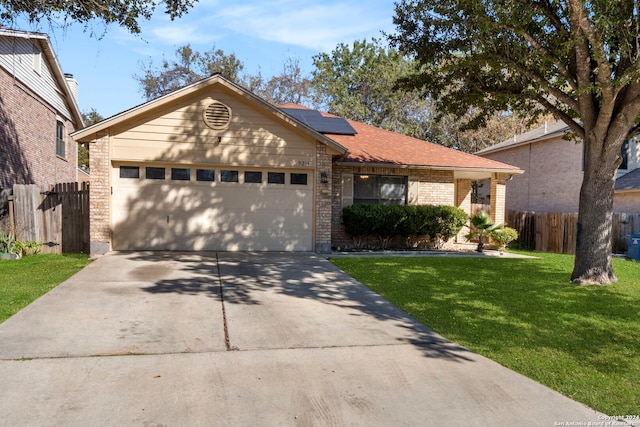 ranch-style home with solar panels, a garage, and a front yard