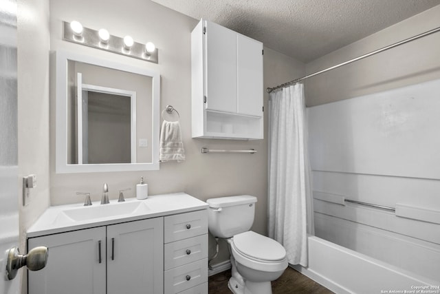 full bathroom with hardwood / wood-style floors, a textured ceiling, toilet, vanity, and shower / tub combo