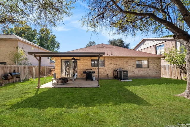 back of house featuring ceiling fan, cooling unit, a fire pit, a patio area, and a lawn