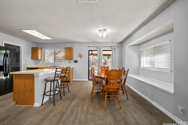 dining room with a textured ceiling, sink, dark wood-type flooring, and a skylight