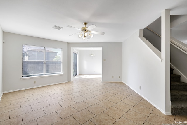 empty room featuring light tile patterned floors and ceiling fan with notable chandelier