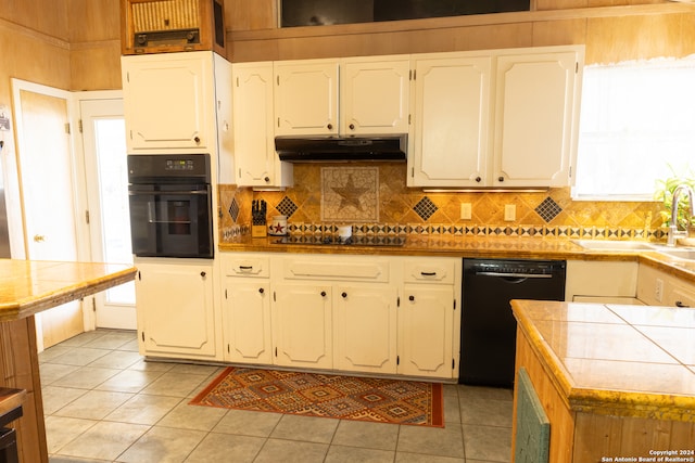 kitchen with light tile patterned floors, sink, tile countertops, and black appliances