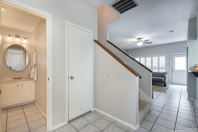 stairway with tile patterned floors, ceiling fan, and sink