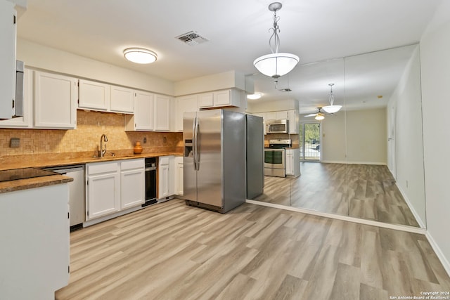 kitchen featuring stainless steel appliances, ceiling fan, sink, pendant lighting, and white cabinets