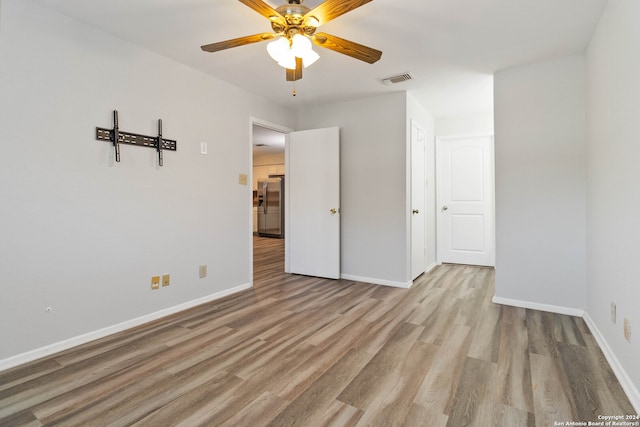 empty room with ceiling fan and light hardwood / wood-style floors