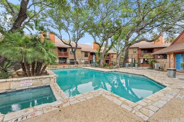 view of swimming pool with central air condition unit, a patio area, and a hot tub