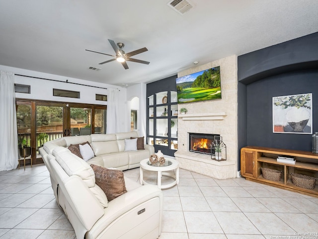 living room with light tile patterned floors, a stone fireplace, french doors, and ceiling fan