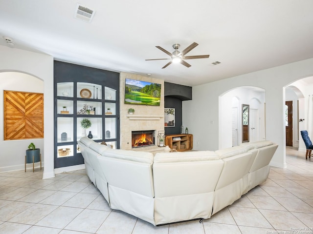 living room with a tile fireplace, ceiling fan, and light tile patterned flooring