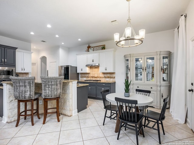 kitchen with gray cabinetry, an inviting chandelier, white cabinets, light stone countertops, and appliances with stainless steel finishes