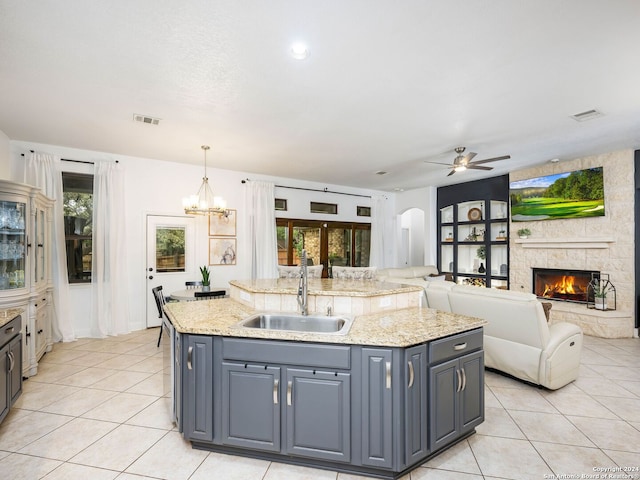 kitchen featuring ceiling fan with notable chandelier, pendant lighting, sink, and an island with sink