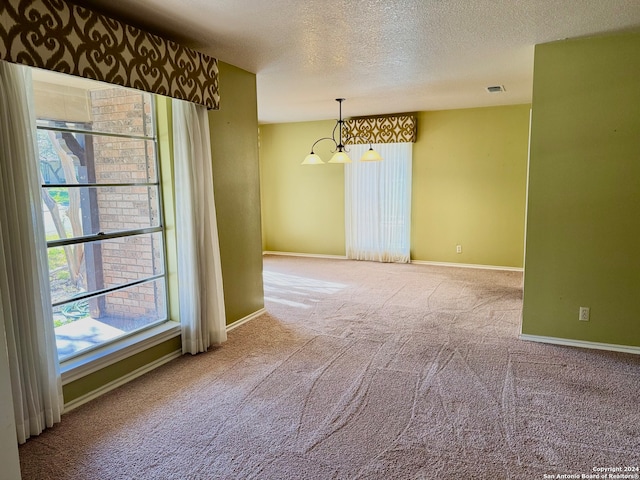 carpeted spare room featuring a textured ceiling and a notable chandelier