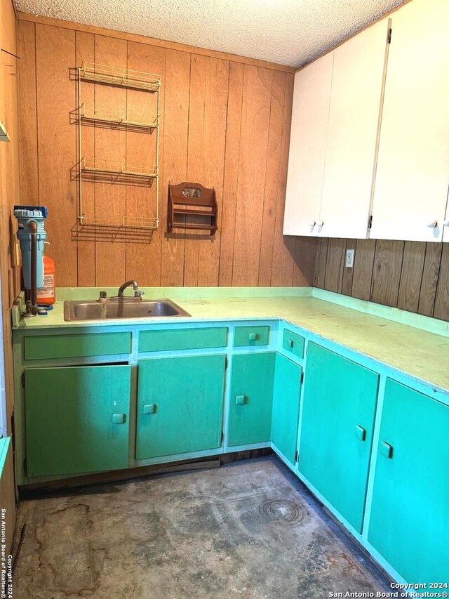 laundry room with a textured ceiling, wooden walls, and sink