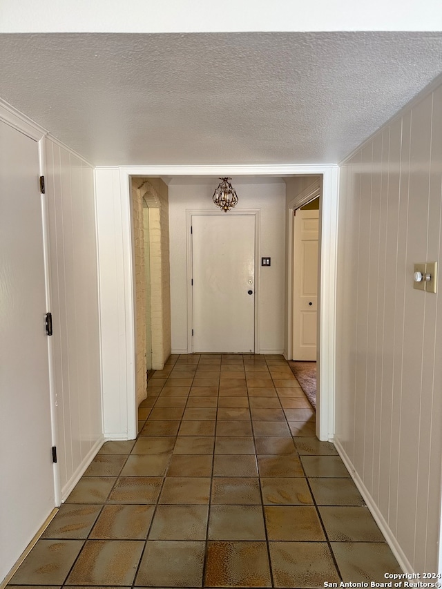 corridor featuring dark tile patterned floors and a textured ceiling