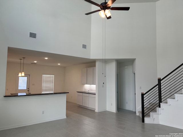 unfurnished living room with a towering ceiling and ceiling fan