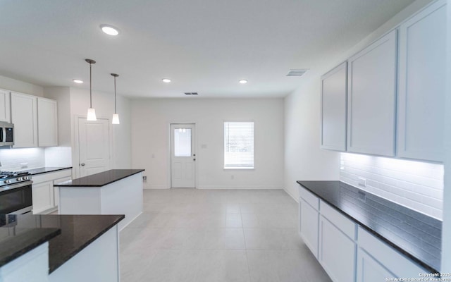 kitchen featuring tasteful backsplash, white cabinetry, decorative light fixtures, and appliances with stainless steel finishes