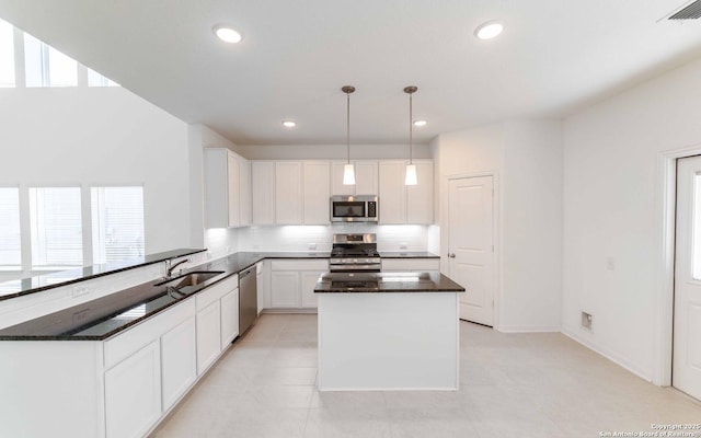 kitchen with sink, hanging light fixtures, kitchen peninsula, white cabinets, and appliances with stainless steel finishes